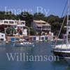 GW29660-60 = View looking North - with traditional Mallorquin wooden llaut departing marina past moored sailing yachts, colourful boat houses, and marina side apartment blocks - near sea entrance to Cala D'Or Marina, Cala D'Or, Santanyi, South East Mallorca, Balearic Islands, Spain. 7th July 2007.